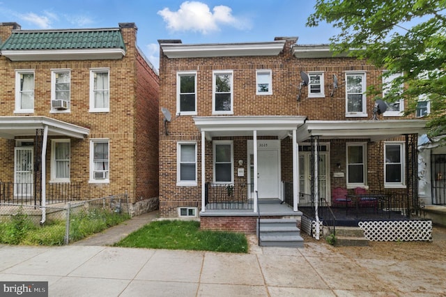 townhome / multi-family property featuring brick siding, covered porch, and fence