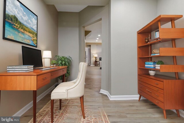 home office with light wood-style flooring and baseboards