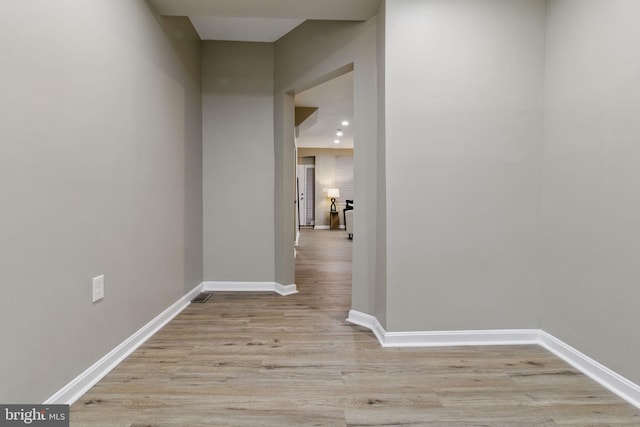 corridor featuring light wood-style flooring and baseboards