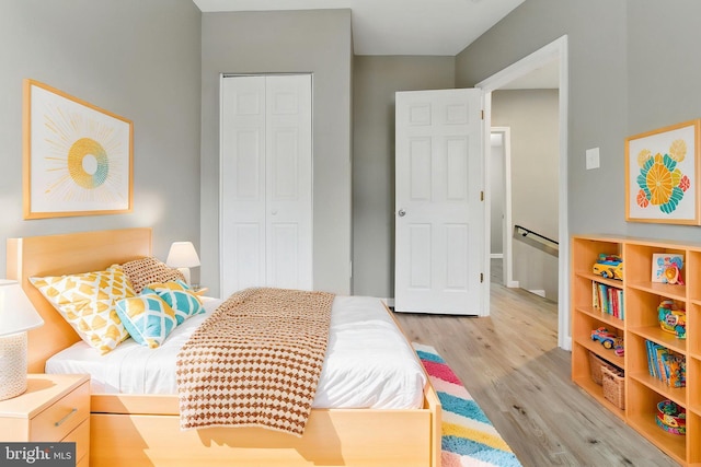 bedroom with wood finished floors, a closet, and baseboards