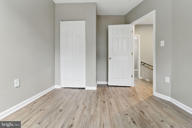 unfurnished bedroom featuring a closet, wood finished floors, and baseboards
