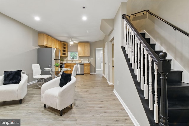living area featuring a ceiling fan, light wood-style flooring, baseboards, stairs, and recessed lighting