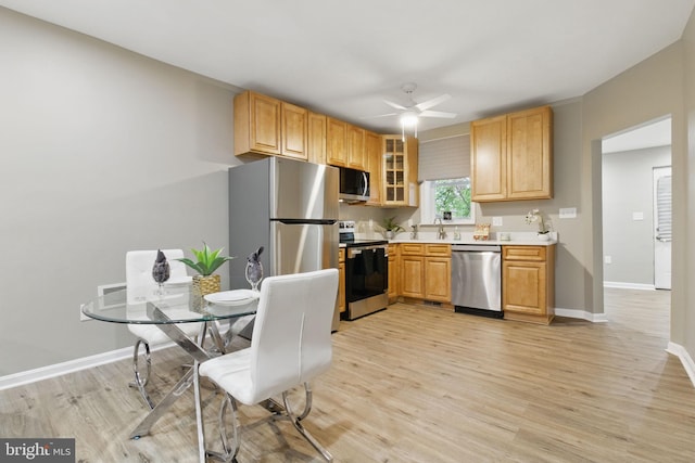 kitchen with appliances with stainless steel finishes, a ceiling fan, light wood-type flooring, and light countertops