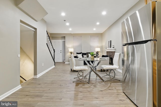 dining area with stairway, baseboards, light wood-type flooring, recessed lighting, and a fireplace