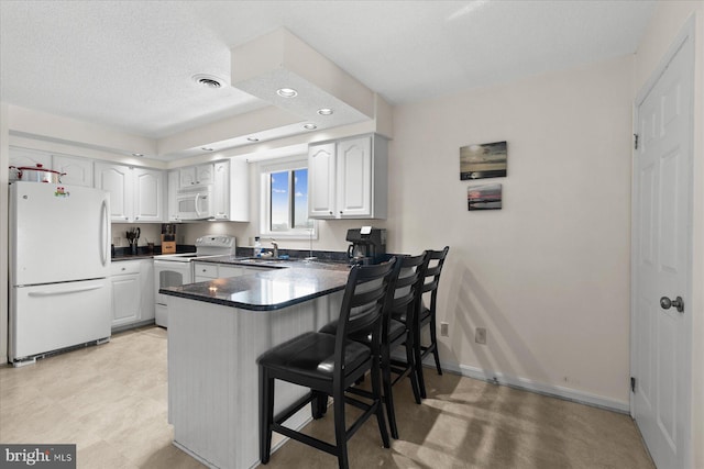 5401 Coastal Hwy Unit 306, Ocean City, MD 21842 - kitchen featuring white appliances, a peninsula, visible vents, a sink, and dark countertops