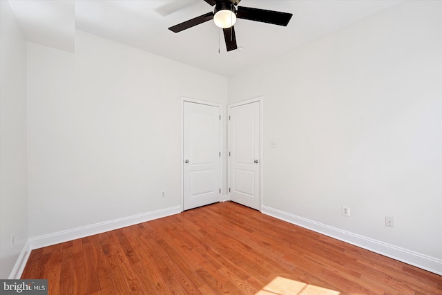 spare room featuring light wood-style floors, ceiling fan, and baseboards
