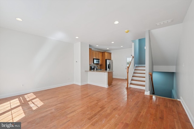 unfurnished living room featuring visible vents, baseboards, and light wood finished floors