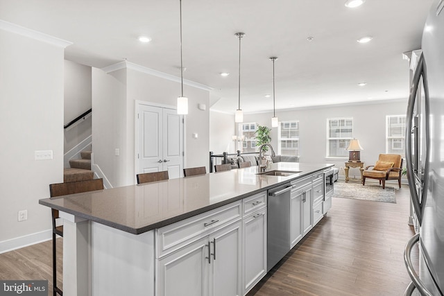 12435 Sea Oaks Ln Unit 3, Berlin, MD 21811 - kitchen featuring crown molding, appliances with stainless steel finishes, a kitchen island with sink, a sink, and dark wood-style floors
