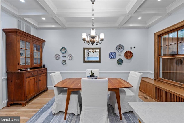 dining space with coffered ceiling, light wood-style flooring, beam ceiling, a chandelier, and ornamental molding