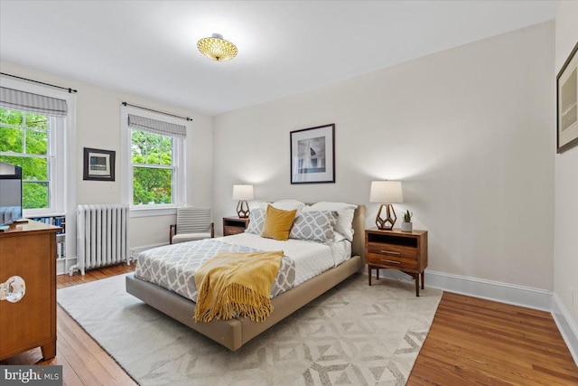 bedroom with radiator, wood finished floors, and baseboards