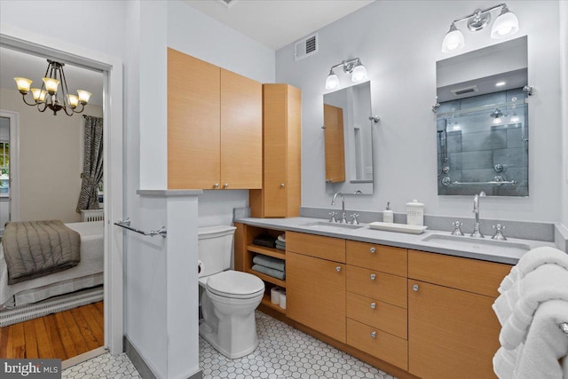 full bathroom featuring double vanity, tiled shower, toilet, and a chandelier