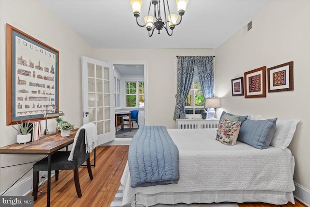 bedroom featuring a chandelier, wood finished floors, french doors, and baseboards