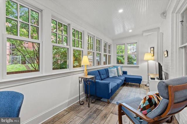 sunroom with baseboards, wood-type flooring, and recessed lighting