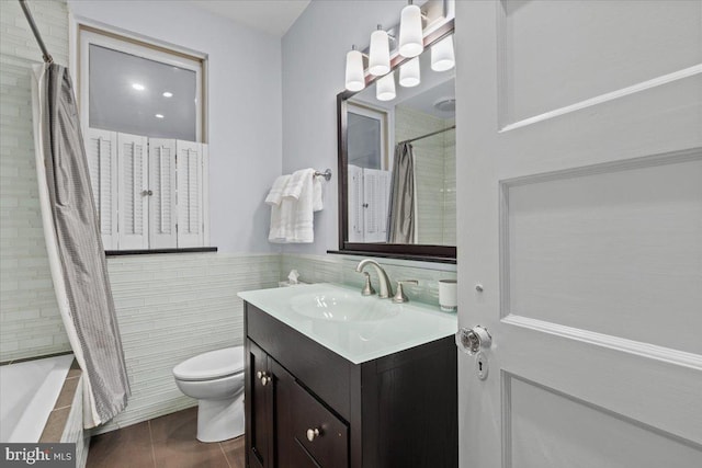 full bathroom with toilet, vanity, tile walls, and tiled shower / bath combo