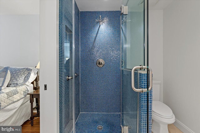 bathroom featuring a stall shower, toilet, and baseboards