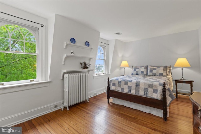 bedroom with radiator, wood-type flooring, and baseboards
