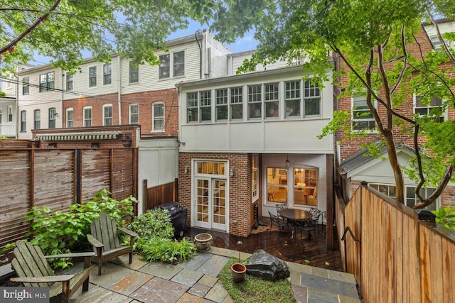 rear view of property featuring brick siding, a fenced backyard, a patio area, and french doors