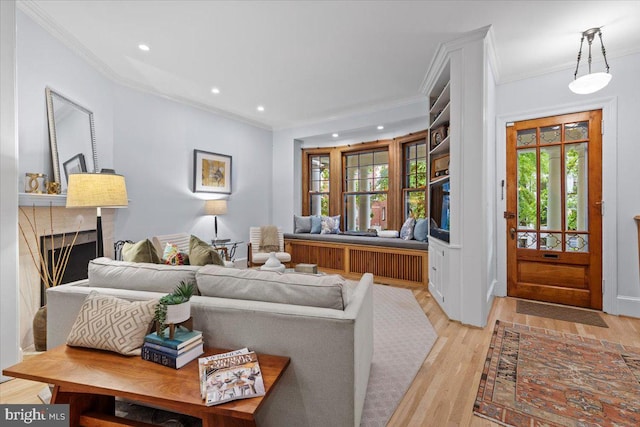 living room featuring a fireplace, crown molding, recessed lighting, and light wood-type flooring