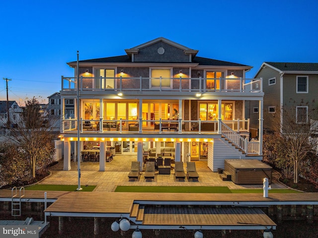 rear view of property with a patio area, outdoor lounge area, a balcony, and a hot tub