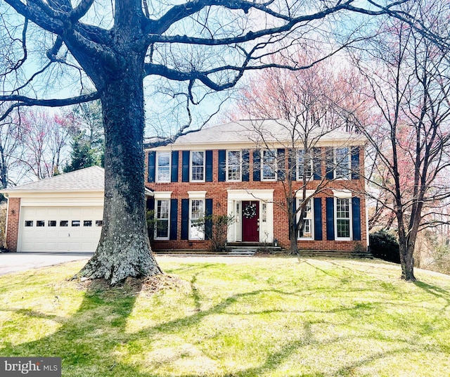 colonial-style house featuring a front lawn, brick siding, driveway, and a garage