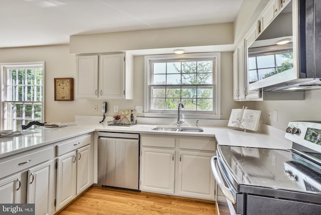 kitchen featuring white cabinets, stainless steel appliances, a sink, light wood-type flooring, and light countertops