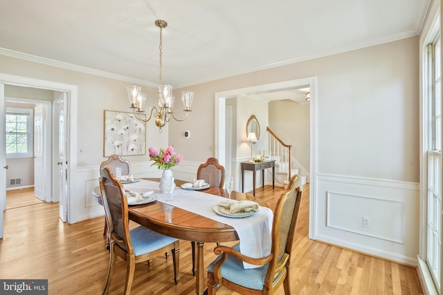 dining space featuring wainscoting, an inviting chandelier, light wood-style floors, and visible vents