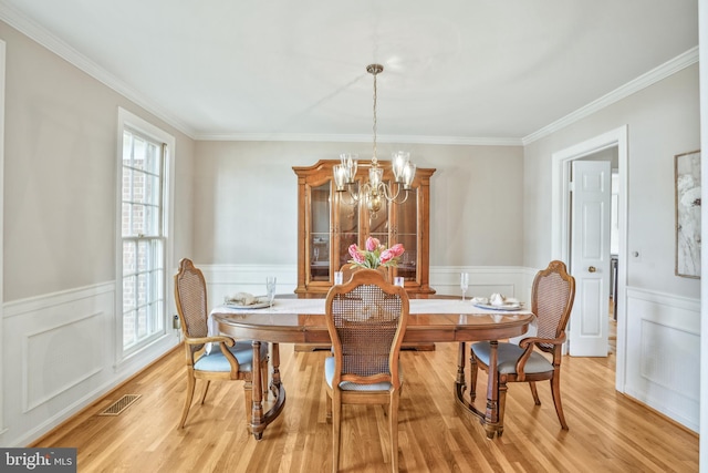dining room with visible vents, crown molding, wainscoting, and an inviting chandelier
