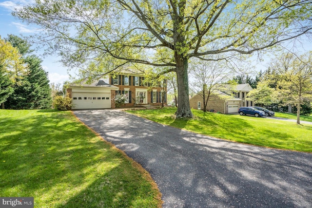 traditional-style home with an attached garage, driveway, and a front lawn
