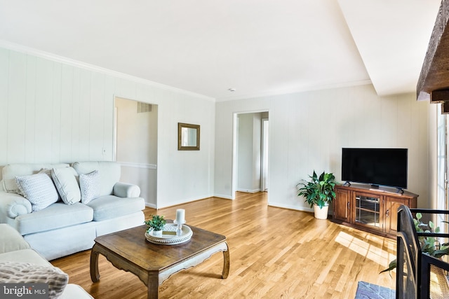 living room featuring light wood-style flooring, visible vents, baseboards, and ornamental molding
