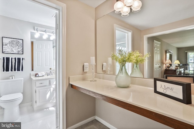 bathroom with baseboards, an inviting chandelier, vanity, and toilet