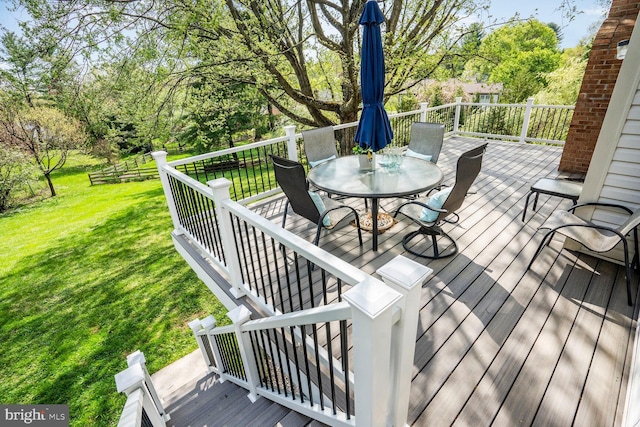 deck featuring outdoor dining area and a yard