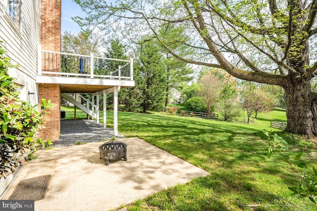 view of yard with a wooden deck, a fire pit, stairs, and a patio