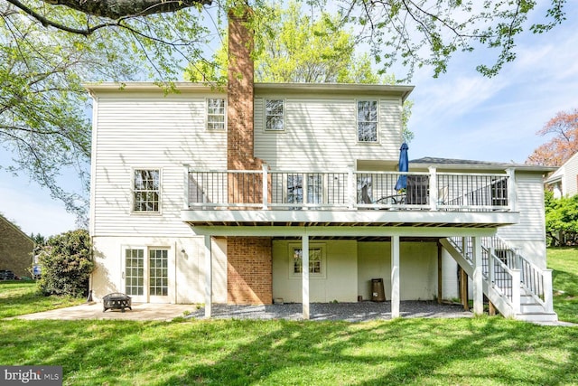 rear view of house featuring a lawn, a deck, a patio, and an outdoor fire pit