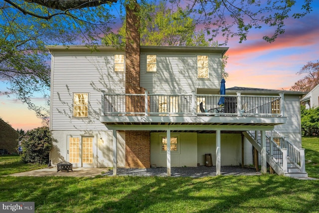 rear view of property featuring stairs, a deck, a yard, a patio, and an outdoor fire pit