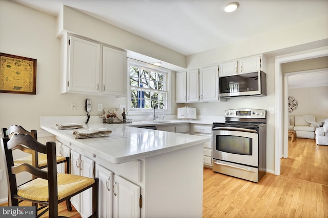 kitchen featuring a peninsula, light countertops, appliances with stainless steel finishes, and white cabinets
