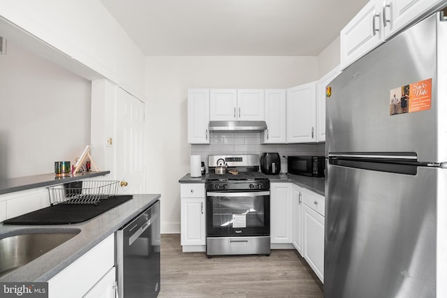1529 E Berks St, Philadelphia, PA 19125 - kitchen with backsplash, white cabinets, under cabinet range hood, appliances with stainless steel finishes, and light wood finished floors