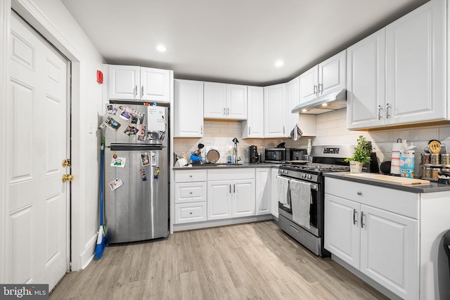 1529 E Berks St, Philadelphia, PA 19125 - kitchen featuring light wood-style floors, under cabinet range hood, white cabinetry, stainless steel appliances, and decorative backsplash