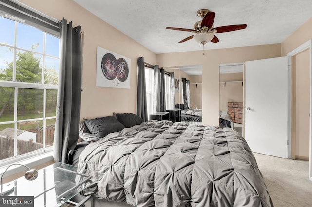 bedroom featuring a textured ceiling, ceiling fan, and light colored carpet