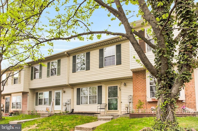 view of property featuring brick siding and a front yard
