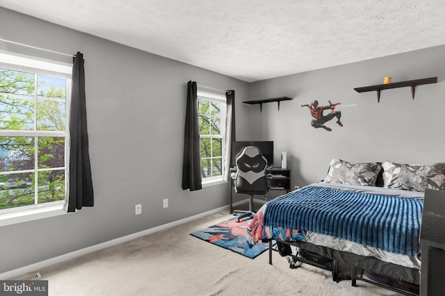 carpeted bedroom featuring a textured ceiling, baseboards, and visible vents