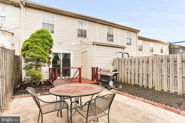 rear view of house with outdoor dining area, a fenced backyard, and a patio