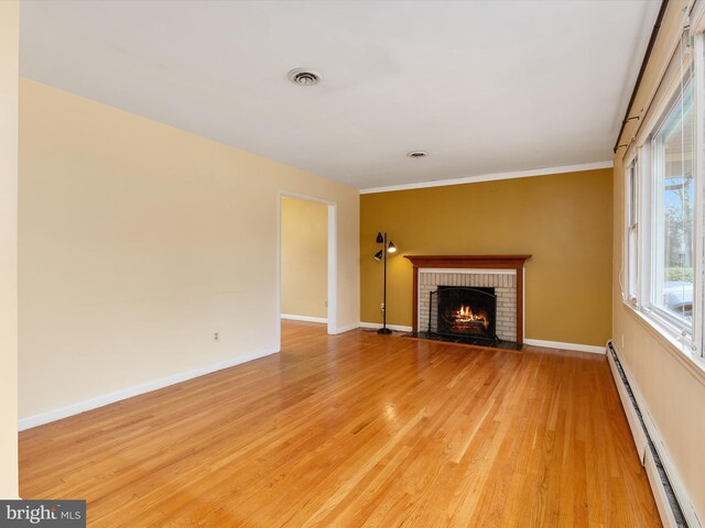 7147 Ohio Ave, Hanover, MD 21076 - unfurnished living room with light wood-type flooring, visible vents, baseboard heating, a brick fireplace, and baseboards