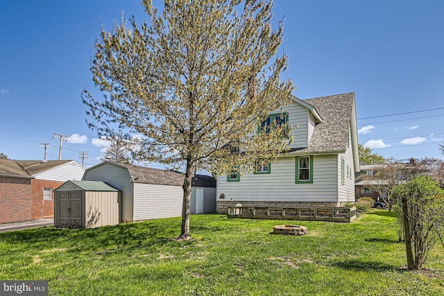 1233 Kahler Ave, Rosedale, MD 21237 - back of house featuring an outbuilding, a lawn, roof with shingles, a storage unit, and a fire pit