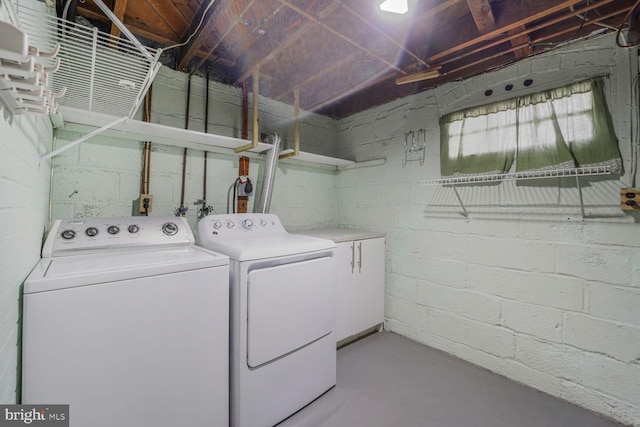 clothes washing area featuring concrete block wall, separate washer and dryer, and laundry area