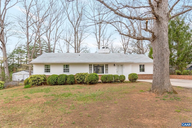 ranch-style home with a chimney, a front lawn, and brick siding