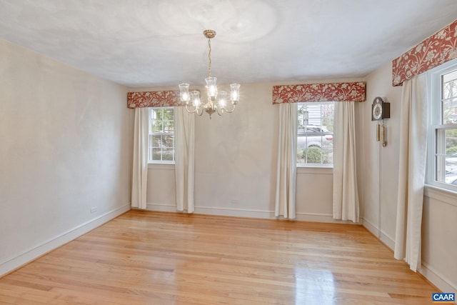 unfurnished dining area with a chandelier, plenty of natural light, and light wood finished floors