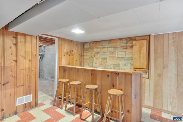 bar with tile patterned floors, wooden walls, visible vents, and a dry bar