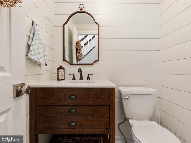 bathroom featuring wooden walls, vanity, and toilet