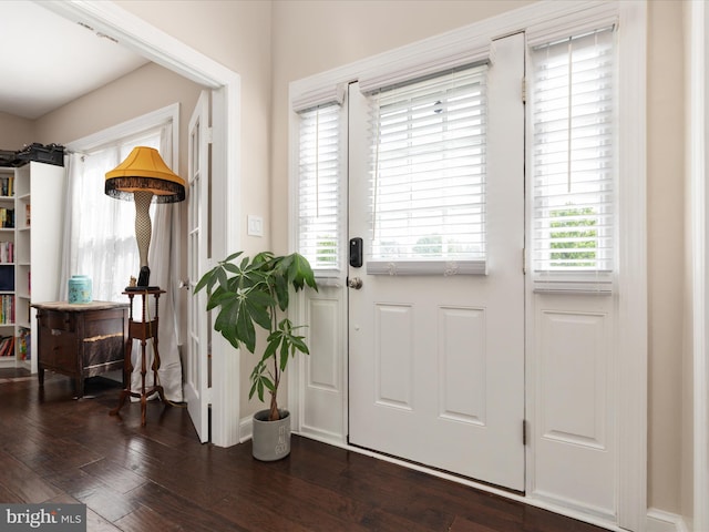 doorway to outside featuring baseboards and dark wood-type flooring