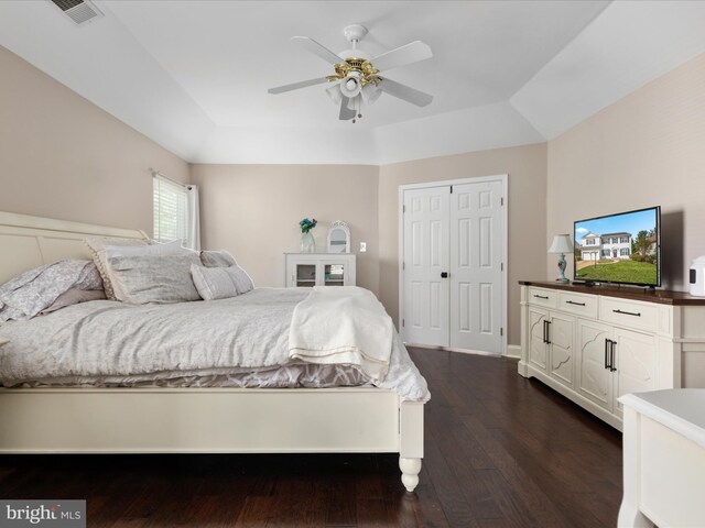 bedroom featuring a raised ceiling, a ceiling fan, dark wood-style floors, and visible vents